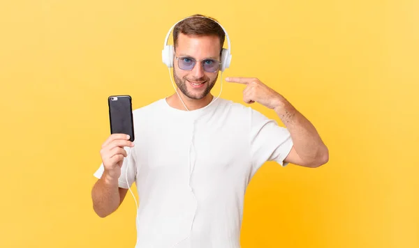 Smiling Confidently Pointing Own Broad Smile Listening Music Headphones Smartphone — kuvapankkivalokuva