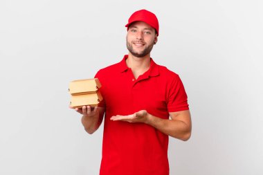 Hamburger dağıtan adam neşeyle gülümsüyor, mutlu hissediyor ve bir konsept gösteriyor.