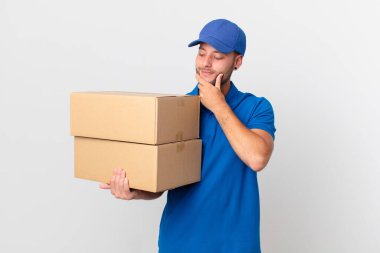 Paket teslim adam mutlu, kendinden emin bir ifade ile gülümseyerek çene üzerinde elle