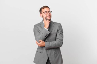 handsome businessman smiling happily and daydreaming or doubting
