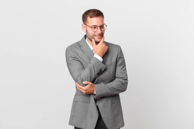 handsome businessman smiling with a happy, confident expression with hand on chin
