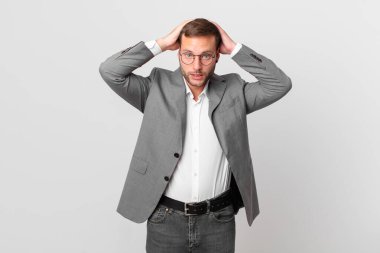handsome businessman feeling stressed, anxious or scared, with hands on head