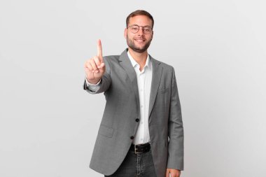 handsome businessman smiling proudly and confidently making number one