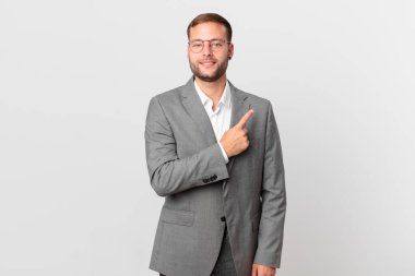 handsome businessman smiling cheerfully, feeling happy and pointing to the side