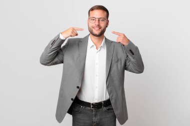 handsome businessman smiling confidently pointing to own broad smile