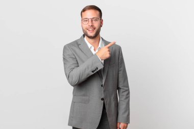 handsome businessman looking excited and surprised pointing to the side