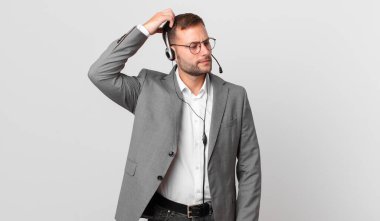 telemarketer businessman feeling puzzled and confused, scratching head
