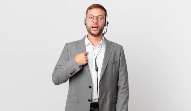 telemarketer businessman looking shocked and surprised with mouth wide open, pointing to self