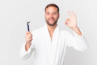 Yakışıklı sarışın adam kendini mutlu hissediyor, iyi bir jestle onaylıyor. traş konsepti