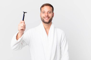 Yakışıklı sarışın adam mutlu bir şekilde gülümsüyor, eli kalçasında ve kendinden emin. traş konsepti