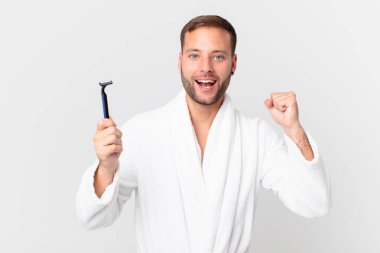 Yakışıklı sarışın adam şokta, gülüyor ve başarıyı kutluyor. traş konsepti