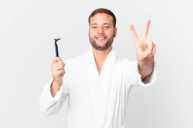 Yakışıklı sarışın adam gülümsüyor ve mutlu görünüyor, zafer ya da barış işareti yapıyor. traş konsepti