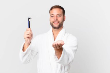 Yakışıklı sarışın adam mutlu bir şekilde gülümsüyor ve bir konsept sunuyor. traş konsepti