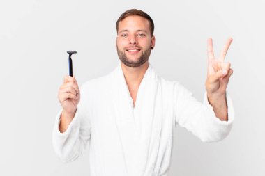 Yakışıklı sarışın adam gülümsüyor ve arkadaş canlısı görünüyor. İki numarayı gösteriyor. traş konsepti