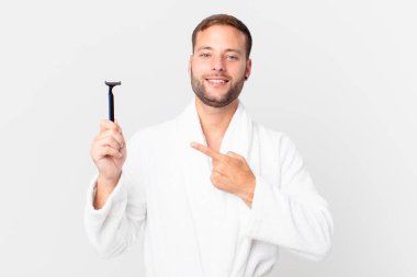 Yakışıklı sarışın adam neşeyle gülümsüyor, mutlu hissediyor ve bir tarafı işaret ediyor. traş konsepti