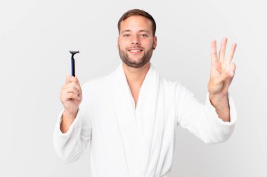 Yakışıklı sarışın adam gülümsüyor ve arkadaş canlısı görünüyor, üç numarayı gösteriyor. traş konsepti