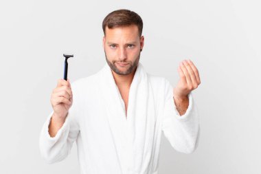 Yakışıklı sarışın adam kapiş ya da para hareketi yapıyor, sana ödemeni söylüyor. traş konsepti