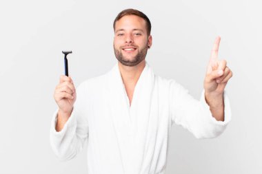 Yakışıklı sarışın adam gülümsüyor ve arkadaş canlısı görünüyor. Bir numarayı gösteriyor. traş konsepti