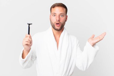 Yakışıklı sarışın adam şaşırmış ve şok olmuş görünüyor. Çenesi düşmüş, elinde bir nesne var. traş konsepti