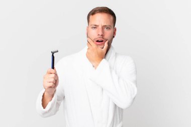 Ağzı ve gözleri açık, eli çenesinde yakışıklı sarışın bir adam. traş konsepti