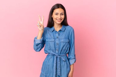 İspanyol güzel kadın gülümsüyor ve arkadaş canlısı görünüyor, iki numarayı gösteriyor.