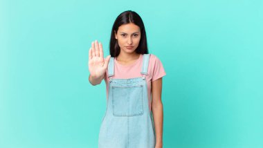 İspanyol güzel kadın ciddi görünüyor. Avuç içini gösteriyor. Durdurma hareketi yapıyor.