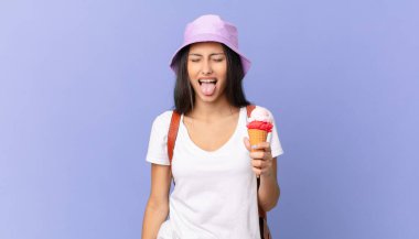 Neşeli ve asi tavırlı İspanyol bir turist, şaka yapıyor, dil çıkarıyor ve dondurma tutuyor.