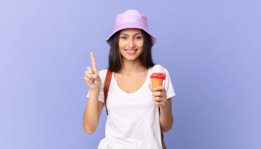 Güzel İspanyol turist gülümsüyor ve arkadaş canlısı görünüyor. Bir numarayı gösteriyor ve elinde dondurma tutuyor.