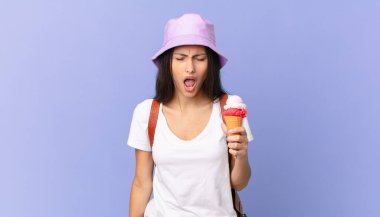 Oldukça İspanyol bir turist agresif bir şekilde bağırıyor, çok kızgın görünüyor ve elinde dondurma tutuyor.