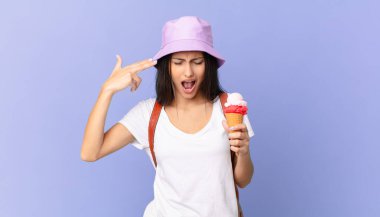 Güzel İspanyol turist mutsuz ve stresli görünüyor, intihar jesti silah işareti yapıyor ve elinde dondurma tutuyor.