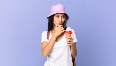 Güzel İspanyol turist düşüncesi, kuşkulu ve kafası karışık ve elinde dondurma tutuyor.