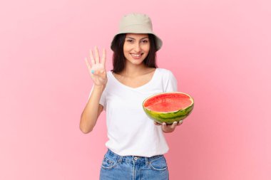 Gülümsüyor ve arkadaş canlısı görünüyor, dört numarayı gösteriyor.