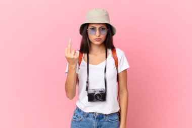 pretty hispanic tourist feeling angry, annoyed, rebellious and aggressive with a photo camera and a hat