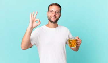 Genç yakışıklı bir adam yarım litre bira içiyor.