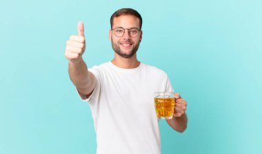 Genç yakışıklı bir adam yarım litre bira içiyor.