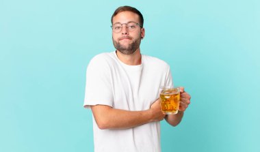 Genç yakışıklı bir adam yarım litre bira içiyor.