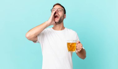 Genç yakışıklı bir adam yarım litre bira içiyor.