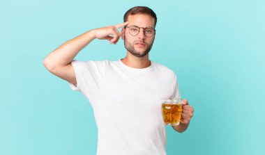 Genç yakışıklı bir adam yarım litre bira içiyor.