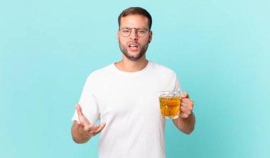 Genç yakışıklı bir adam yarım litre bira içiyor.