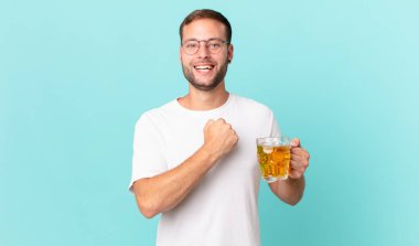 Genç yakışıklı bir adam yarım litre bira içiyor.