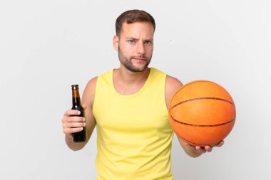 Elinde bira ve basketbol topu olan yakışıklı bir adam. Zaferi kutluyoruz