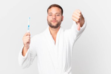 Bornoz giyen ve elinde diş fırçası tutan yakışıklı bir adam.