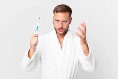 Bornoz giyen ve elinde diş fırçası tutan yakışıklı bir adam.