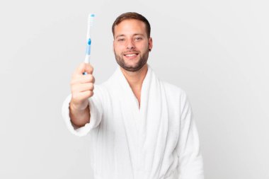 Bornoz giyen ve elinde diş fırçası tutan yakışıklı bir adam.