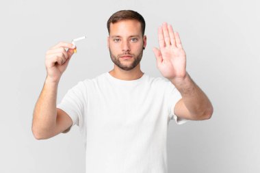 Yakışıklı adam sigarayı kırık bir puroyla bırakıyor.