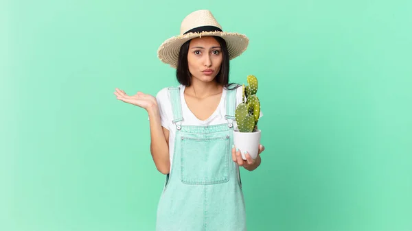 Pretty Farmer Woman Feeling Puzzled Confused Doubting Holding Cactus — Foto de Stock