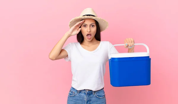 Pretty Hispanic Woman Looking Happy Astonished Surprised Holding Portable Refrigerator — Stock Photo, Image