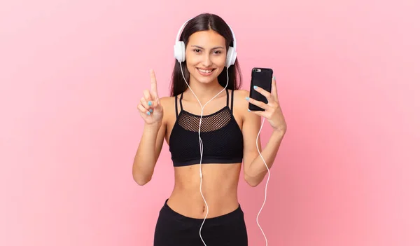 Hispanic Fitness Woman Smiling Looking Friendly Showing Number One Headphones — Stock Photo, Image