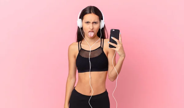 Hispanic Fitness Woman Feeling Disgusted Irritated Tongue Out Headphones Phone — Foto Stock