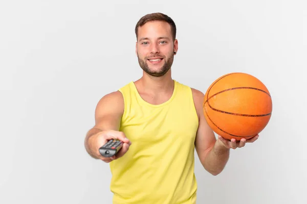 バスケットボールボールを持ったハンサムな男とコントローラー付きのチャンネルを選ぶ — ストック写真
